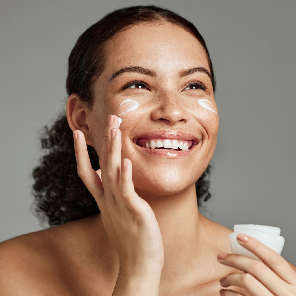 Happy smiling girl with perfect skin with moisturizing face cream on a cheek. Skin care and health concept | Melindas Med-Spa & Salon in North Myrtle Beach SC